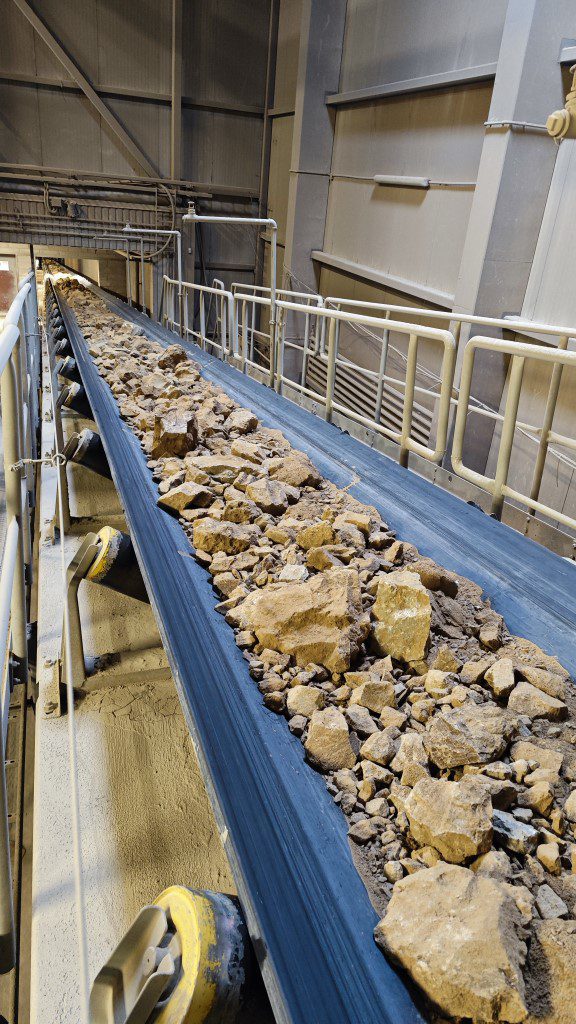 Juostinis transporteris su dubens formos gumine juosta ir tvirta plienine konstrukcija gabena rūdą kasykloje.